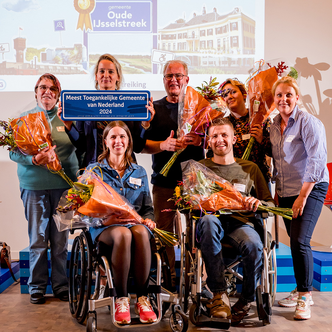 Wethouder Janine Kock houdt een bord omhoog met de tekst Meest Toegankelijke Gemeente va Nederland. Ze staat te midden van vijf leden van de stichting Onbeperkt Meedoen en rechts staat beleidsmedewerker Esther Pol (foto van Evelien Hogers)