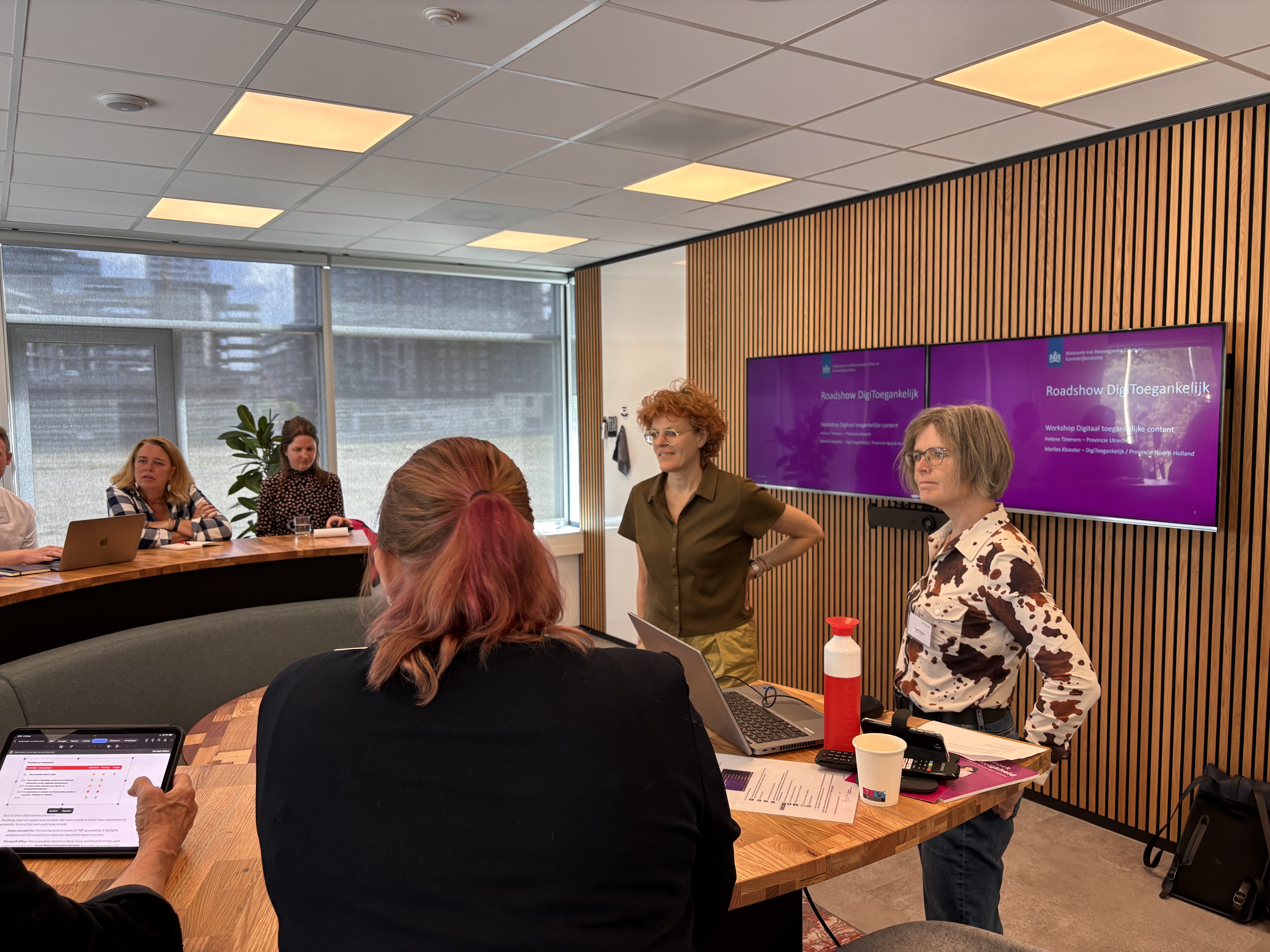Marlies en Helene staan voor een groep mensen die met hun laptop opengeklapt de workshop volgen