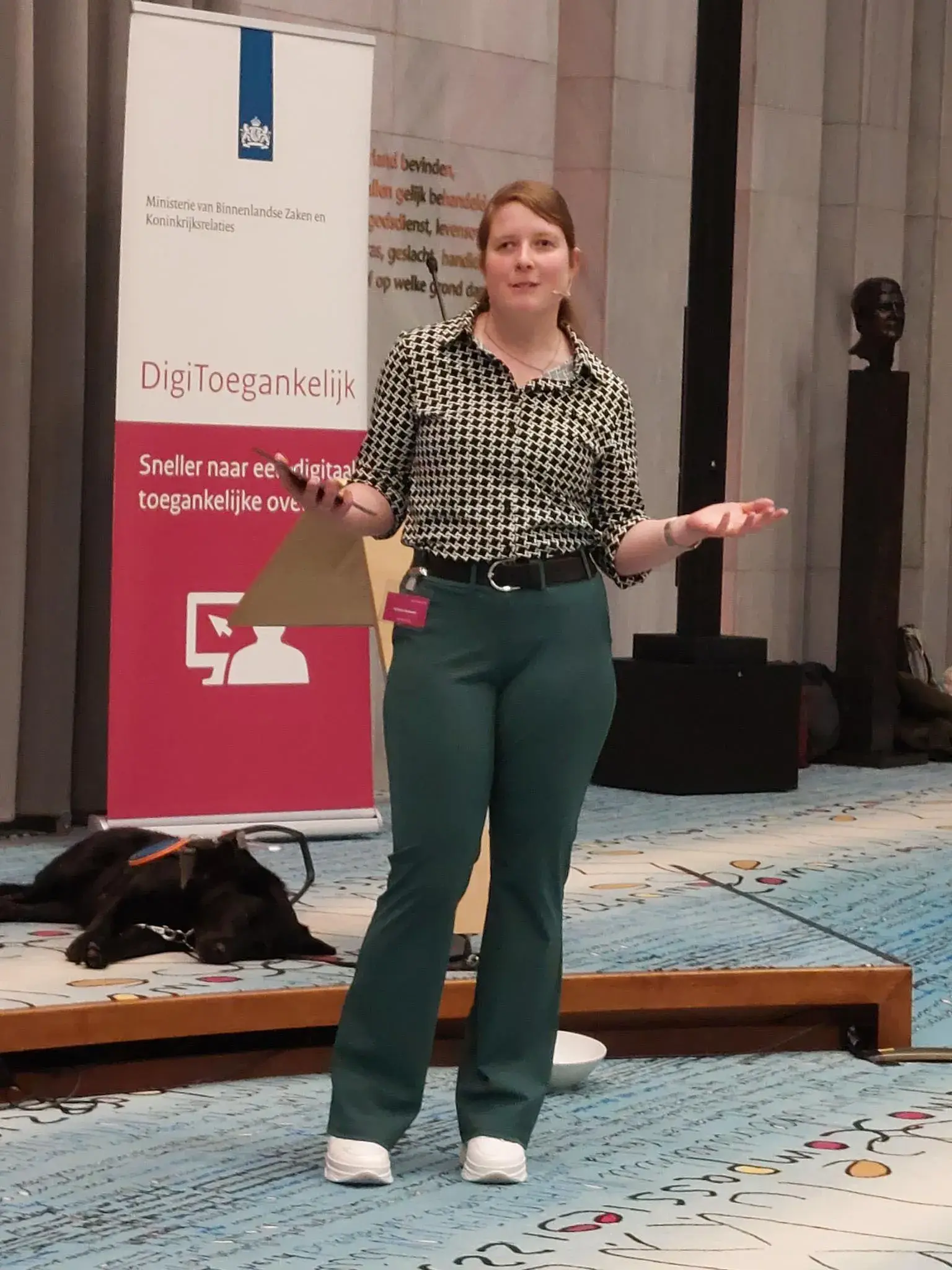 Larissa Klaassen presenteert de roadshow in Arnhem met liggend achter haar haar hulphond Diamond